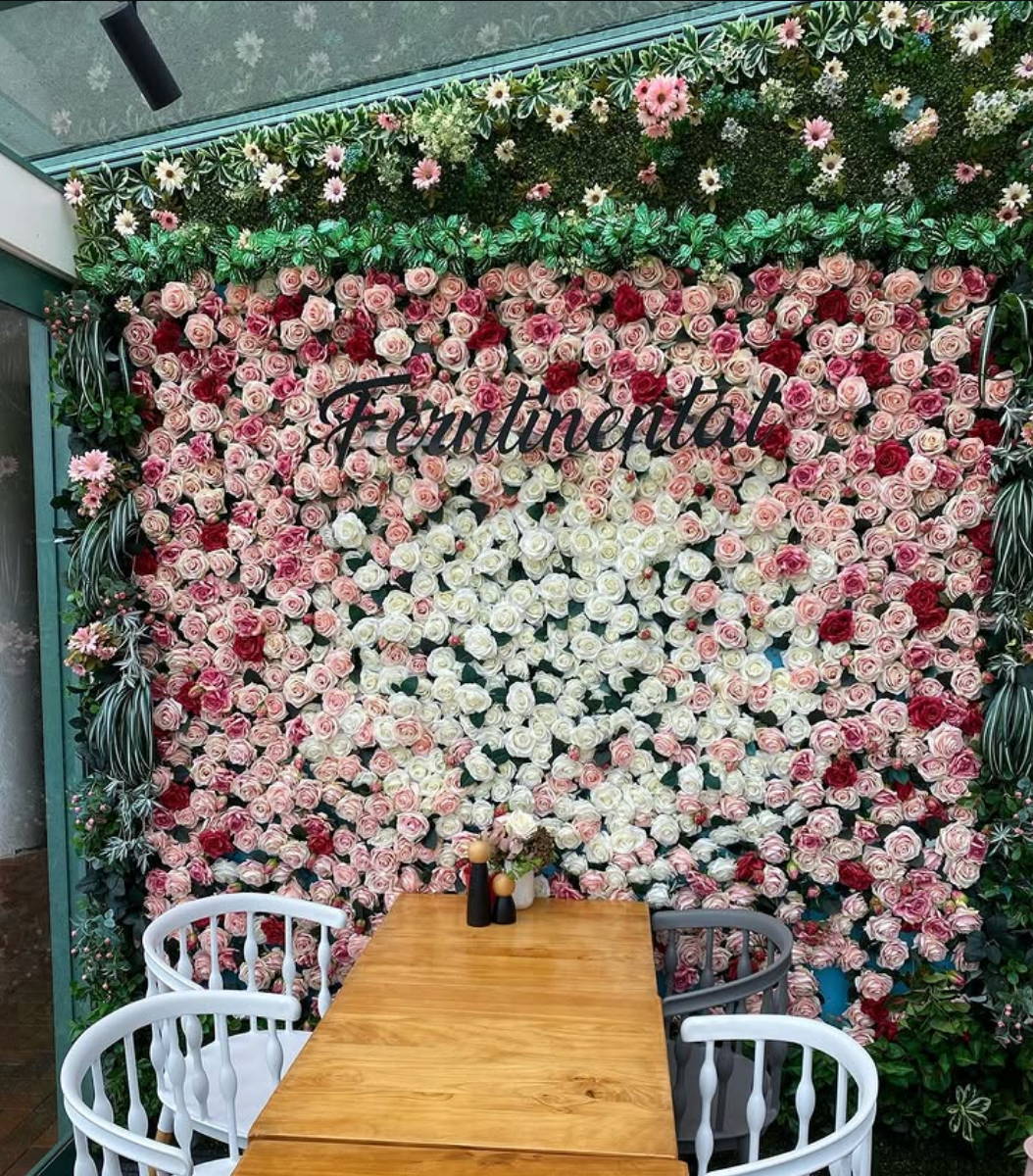 Rose-covered floral wall backdrop with a styled dining table